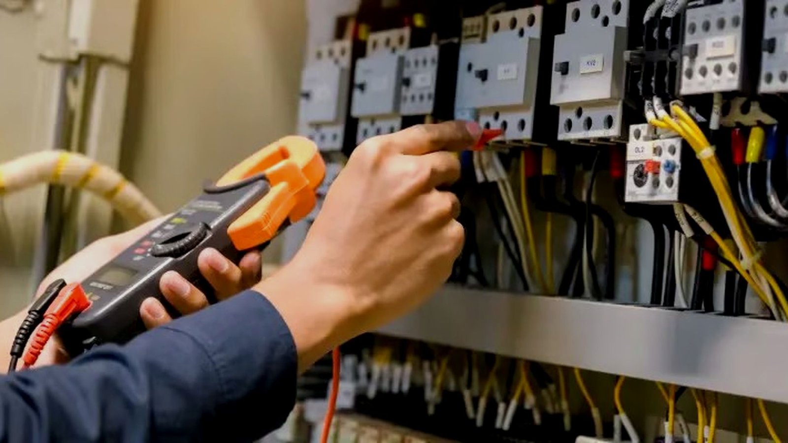 Electrician tracing a fault at an electrical panel with a multimeter